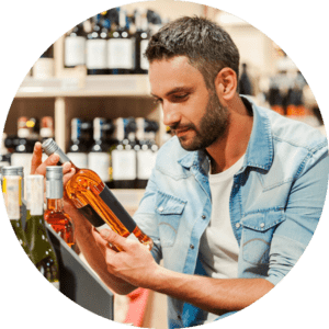 Hombre mirando un vino antes de comprarlo en una Botillería